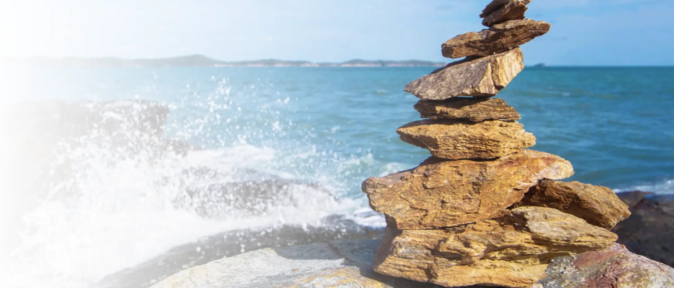 a cairn of craggy stones stacked near ocean spray